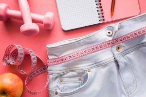Fitness graph with measure tape, weights, notepad and apple
