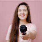 Woman offering microphone graphic on pink background