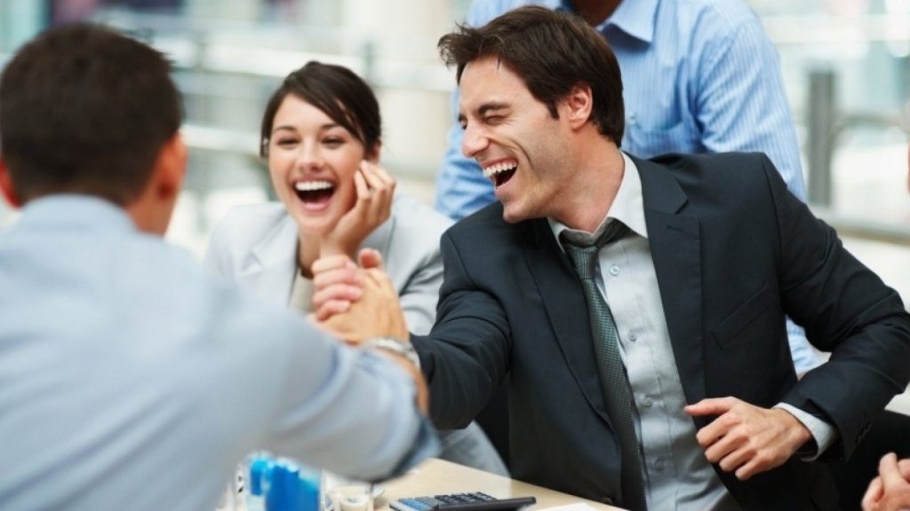 Office executives laughing and shaking hands