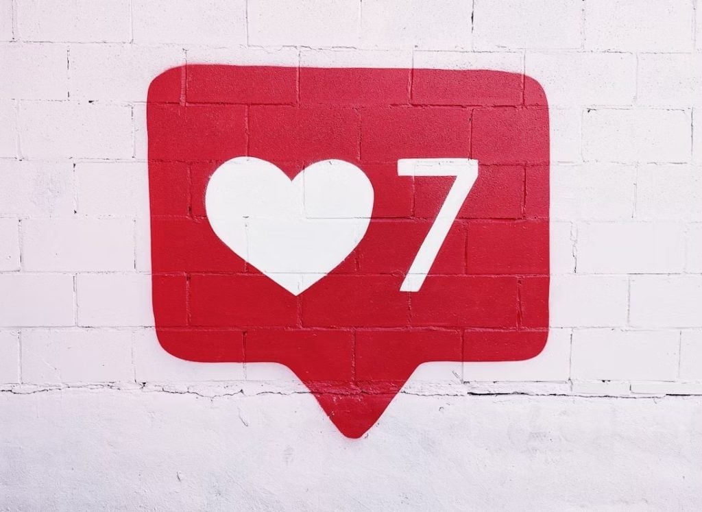 A social media-like red icon painted on a white wall