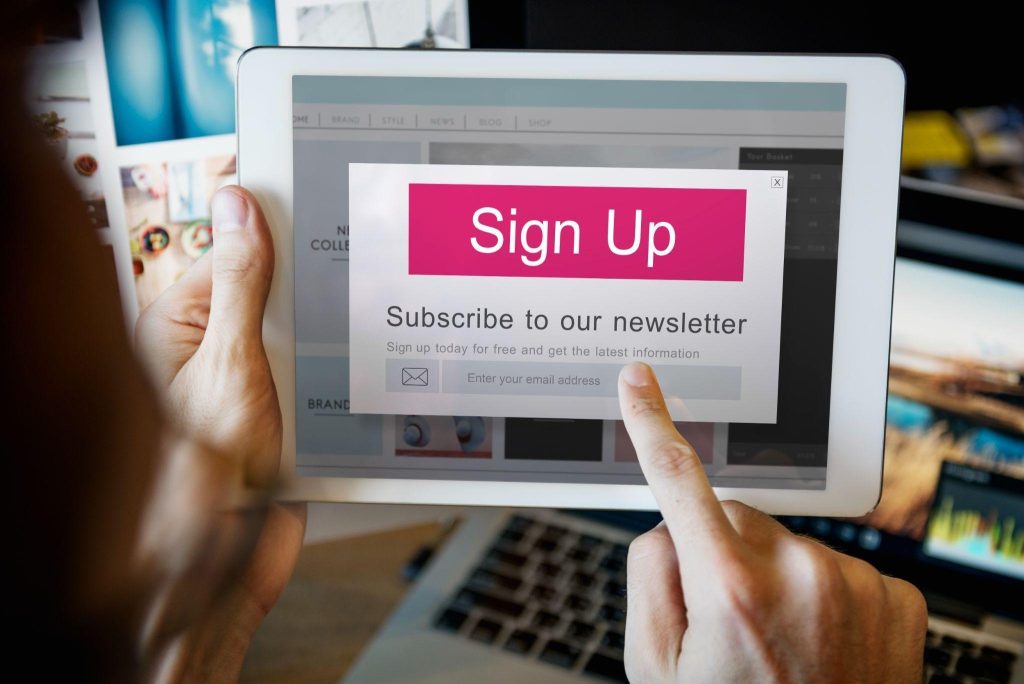 Person tapping a subscribe to our newsletter sign-up button on a tablet screen