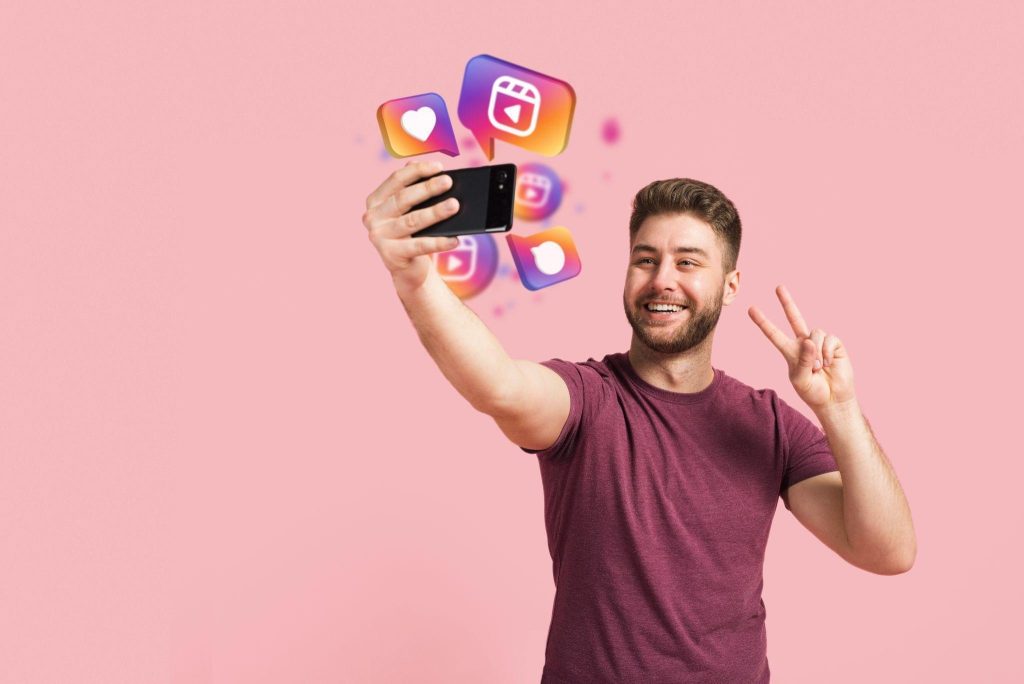 Young man recording a selfie video on smartphone with Instagram Reels icons floating nearby