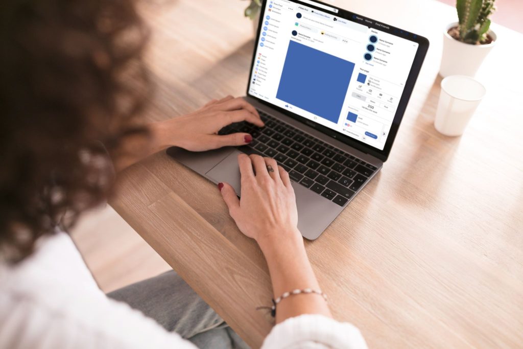 Woman working on laptop with Facebook page open.