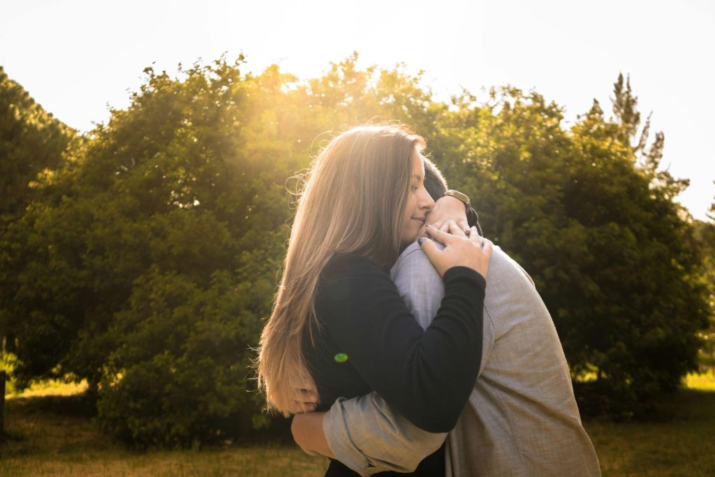 Couple embracing outdoors with warm sunlight for National Hugging Day wellness campaigns