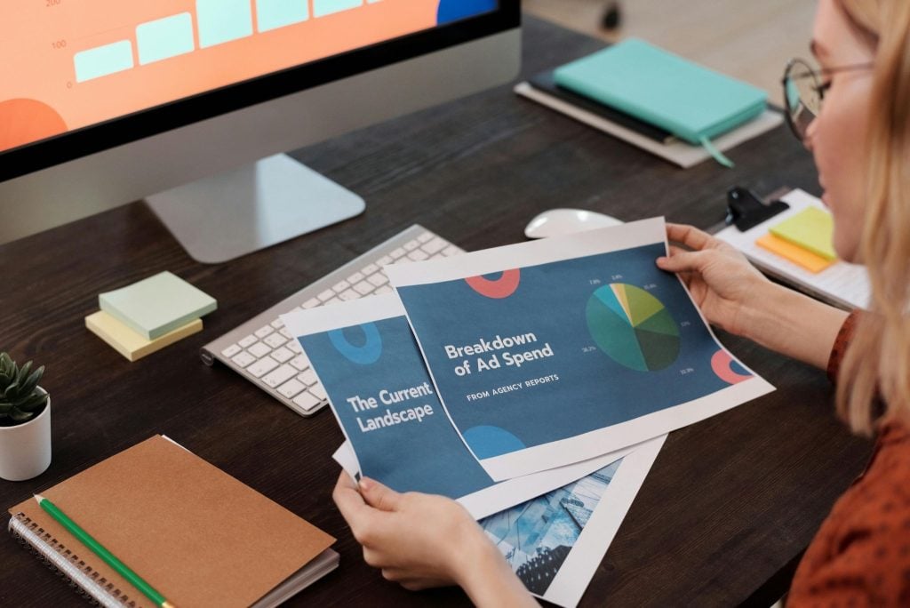 Person reviewing printed marketing reports.