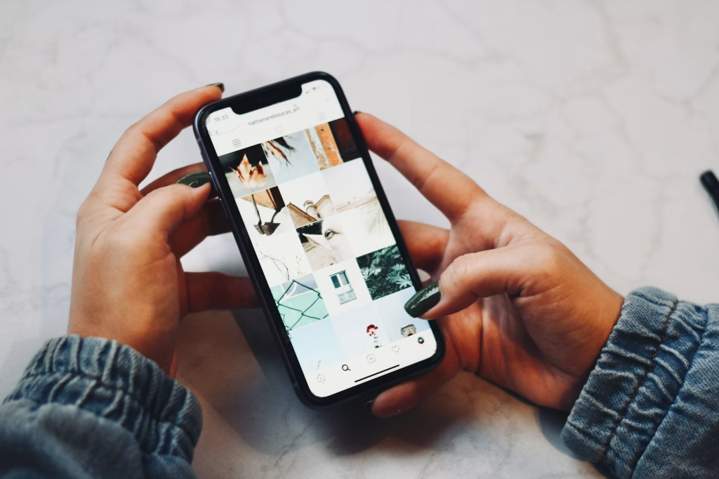 Person holding a black iPhone and posting on Instagram.
