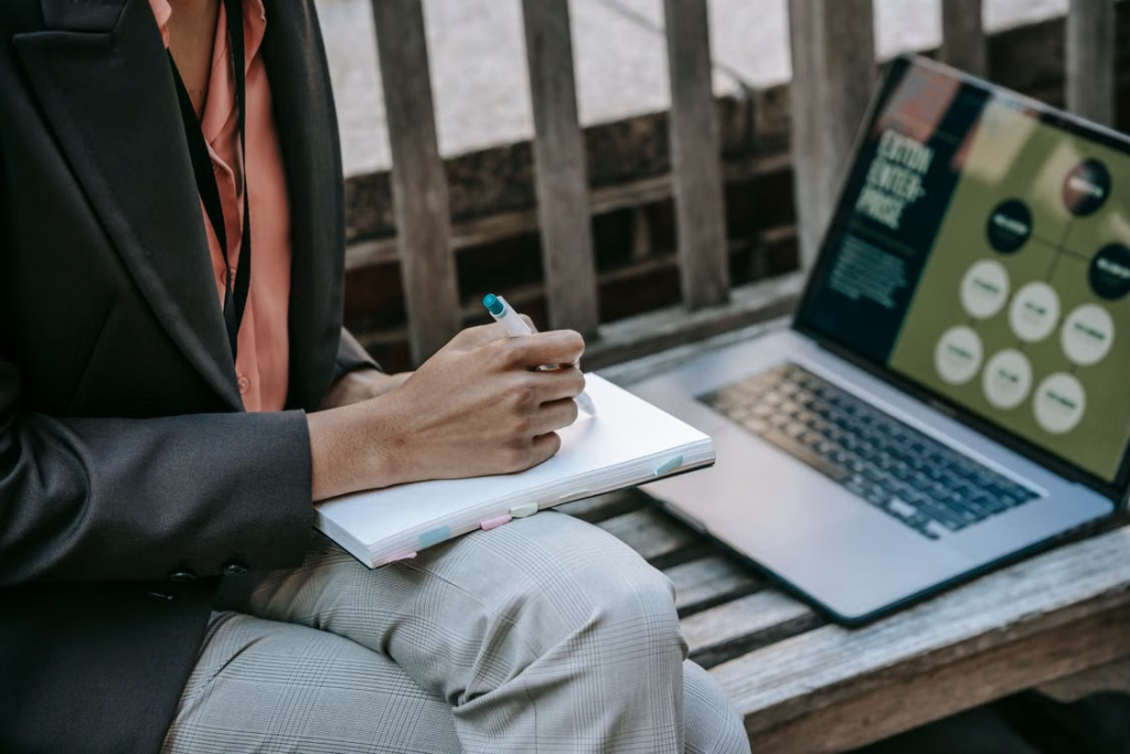 Digital marketing professional doing social listening beside a laptop in an outdoor setting.