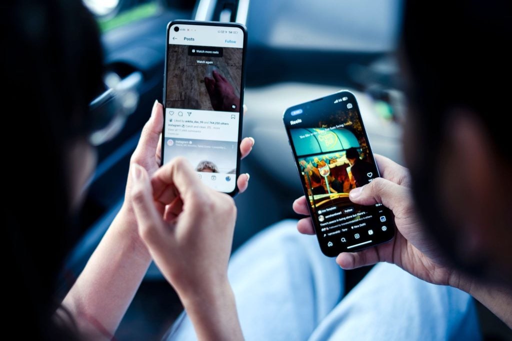 Two people checking their Instagram feed and Instagram Reels on their phone