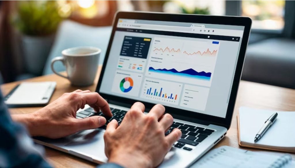 Person typing on laptop showing analytics dashboard with traffic charts and conversion graphs.