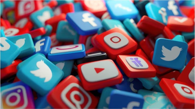 Pile of 3D social media app icons, including Facebook, Twitter, YouTube, and Instagram, in red and blue.